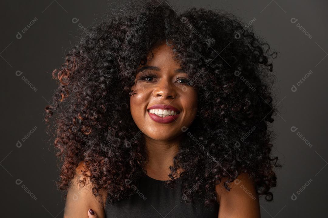 Jovem afro americana com cabelos cacheados olhando para a câmera e sorrindo Linda garota