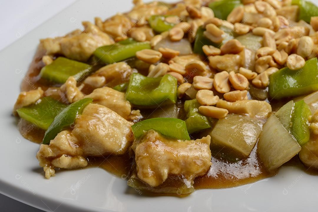 Frango de xadrez em prato verde sobre fundo de madeira - comida chinesa.