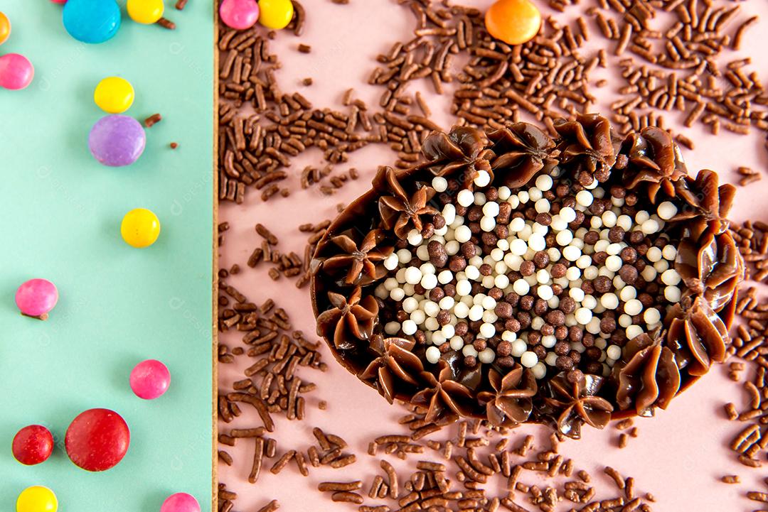 Easter egg filled with chocolate on a colored background with sprinkles and confetti