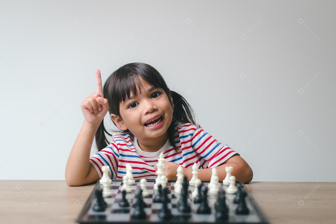 Menina asiática jogando xadrez em casa. um jogo de xadrez [download] -  Designi