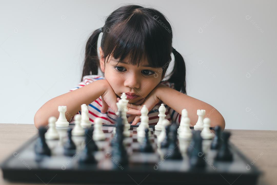 Menina asiática jogando xadrez em casa. um jogo de xadrez