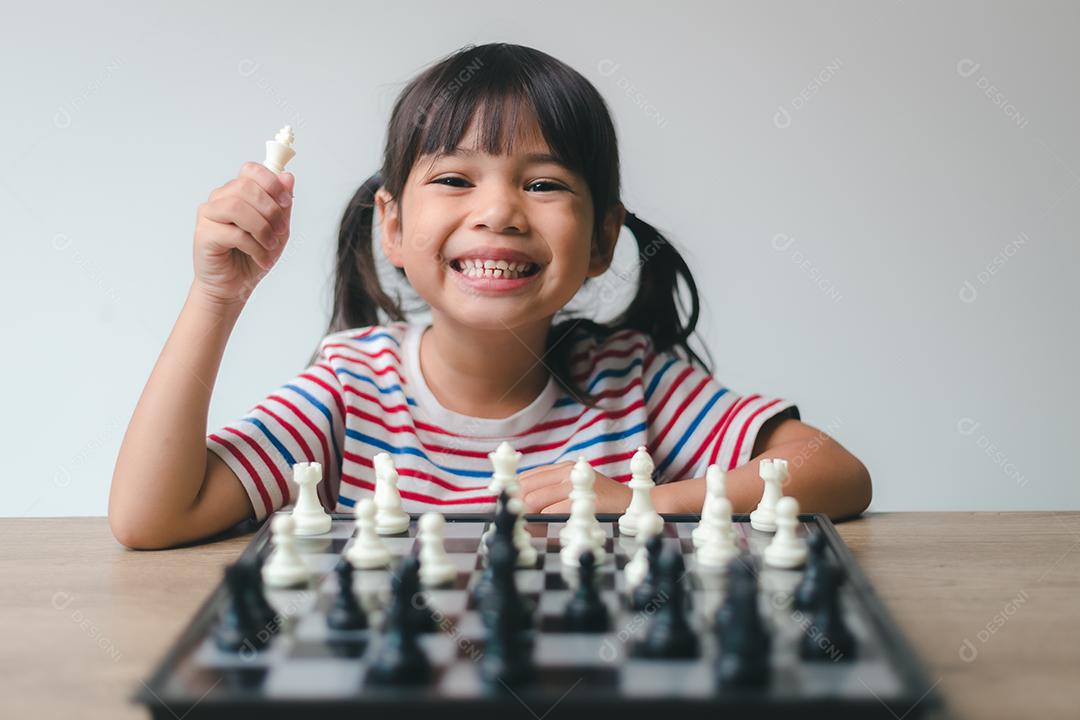 Menina asiática jogando xadrez em casa. um jogo de xadrez