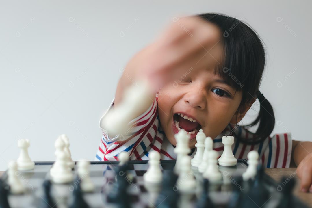 Menina asiática jogando xadrez em casa. um jogo de xadrez
