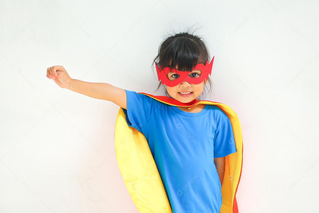 A cute little girl with dressed up and wearing mask and superhero child cape.