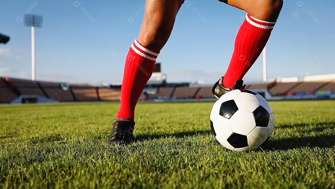Um jogador de futebol chuta uma bola de futebol em um campo