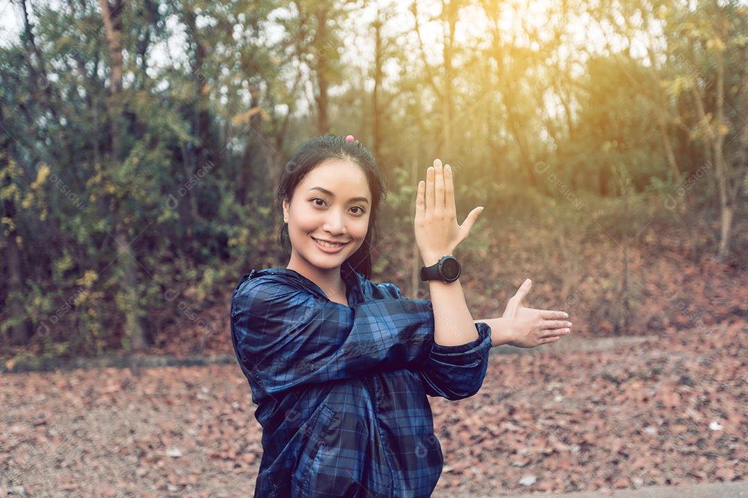 Asian athletic woman warming up and young female athlete exercising and stretching in a park before jogging outdoors