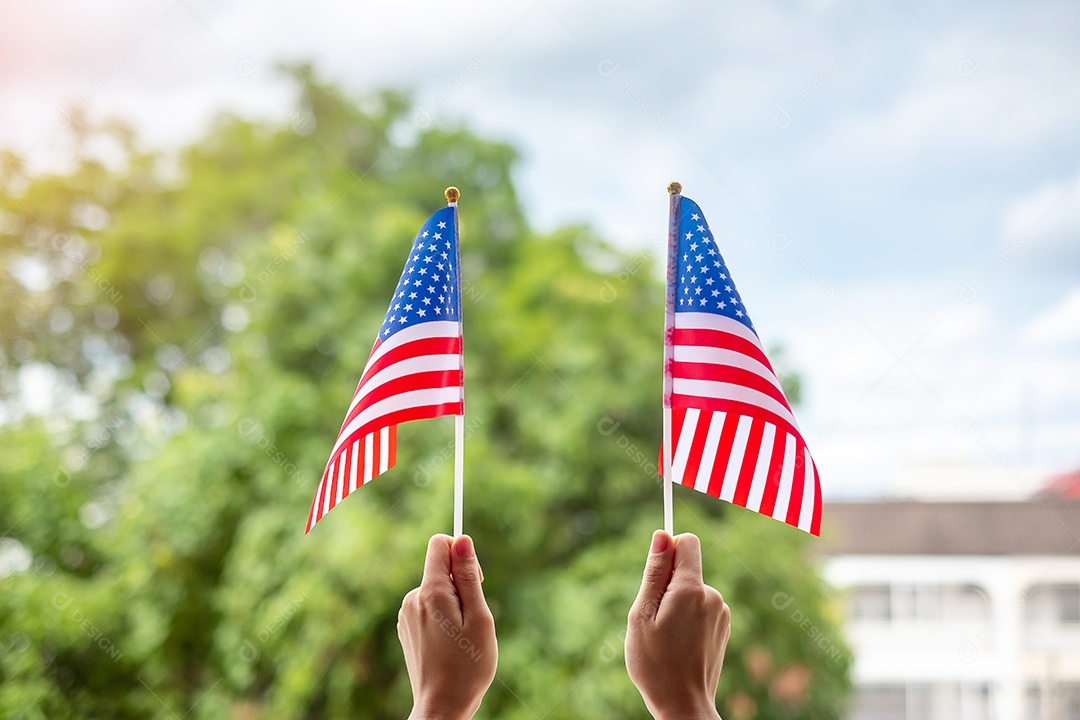 hand holding United States of America flag on blue sky background