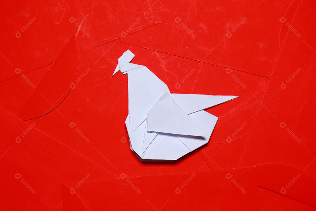 Ofício de origami artesanal de galo dobrado de papel em fundo de pacotes vermelhos é o ano