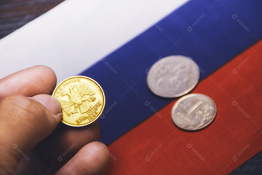 Moeda de rublo de ouro na mão e a bandeira da Rússia no fundo download Designi