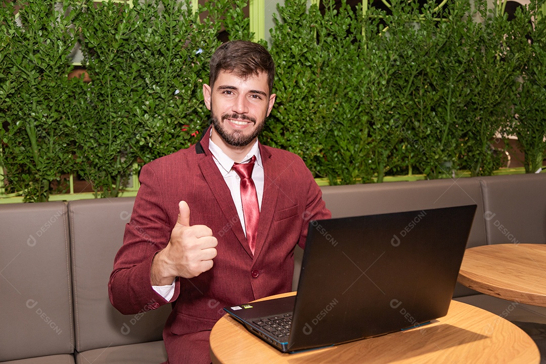 Homem de terno, trabalhando com o laptop, segurando nas mãos o
