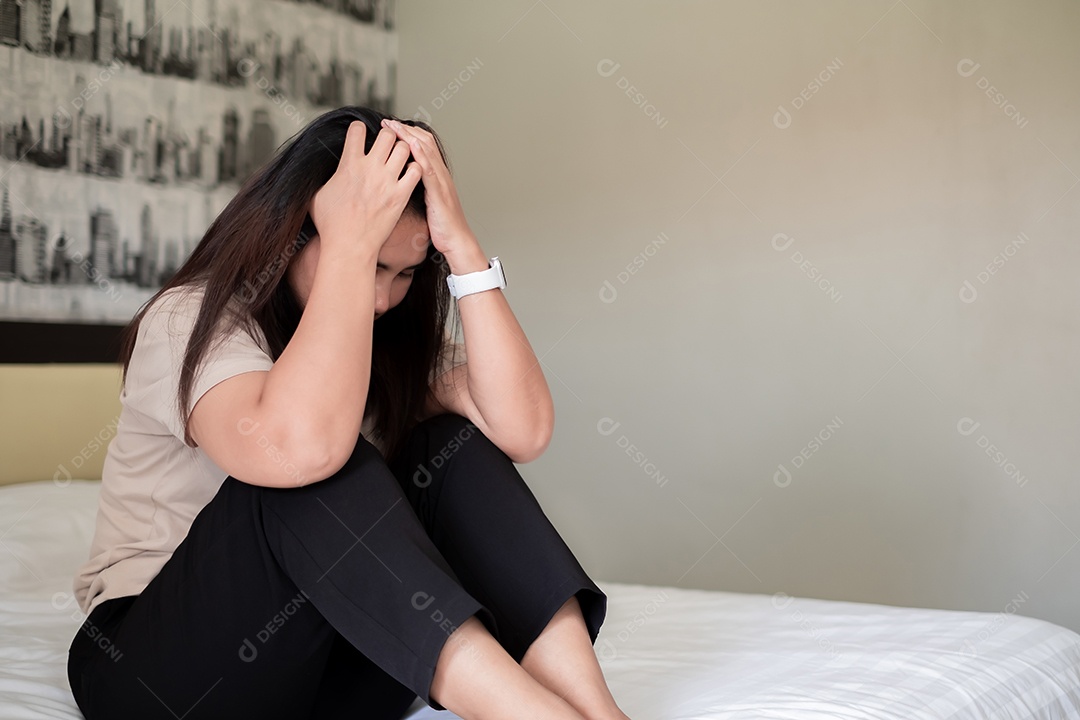 Vista traseira da triste mulher asiática adulta sentada na cama no