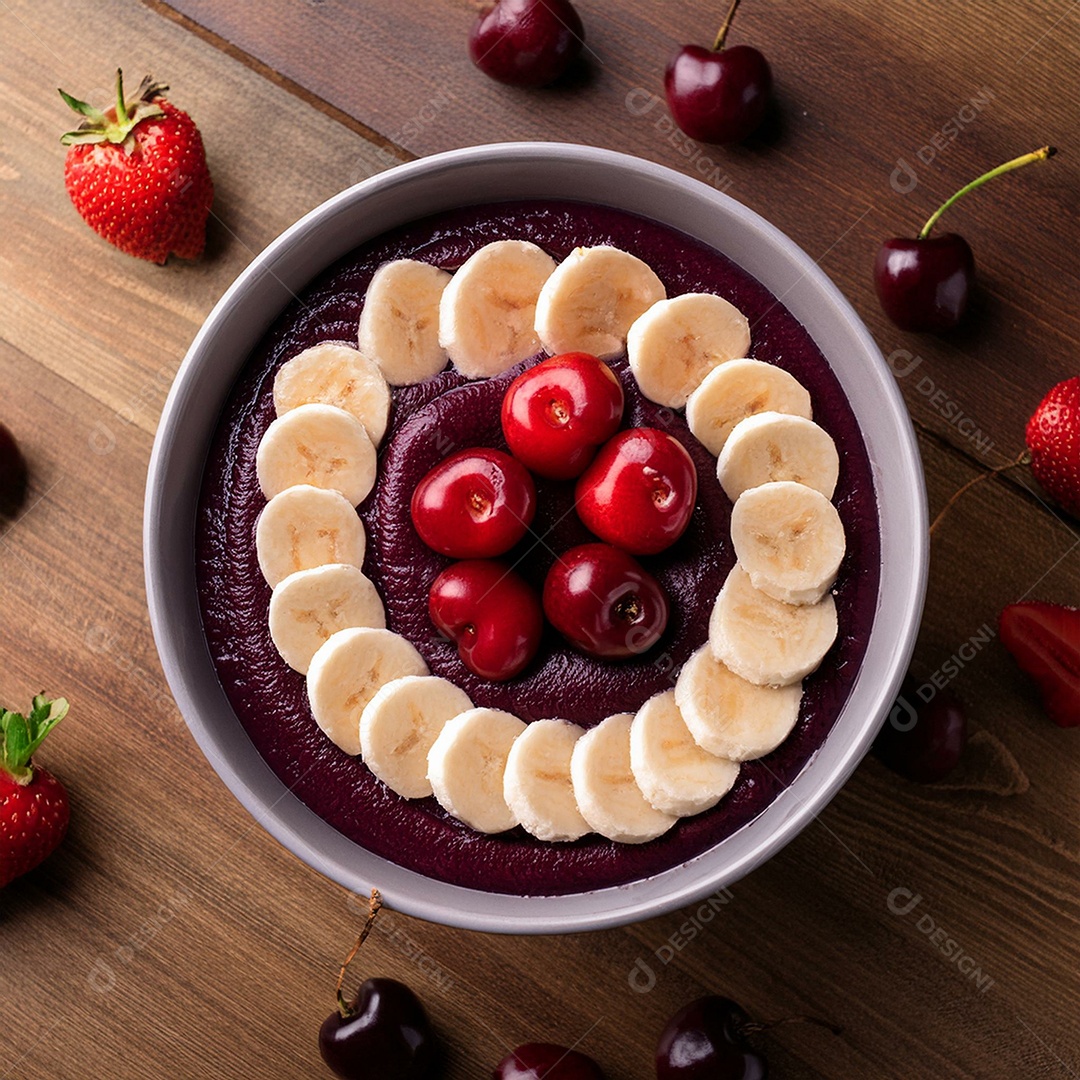 Top view of a bowl full of creamy açaí with cherries and strawberries above