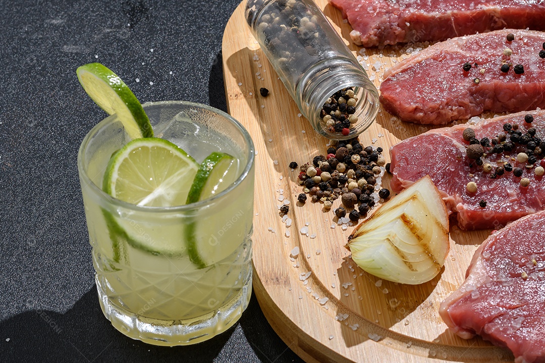 Table with seasoned meat and a glass of barbecue caipirinha