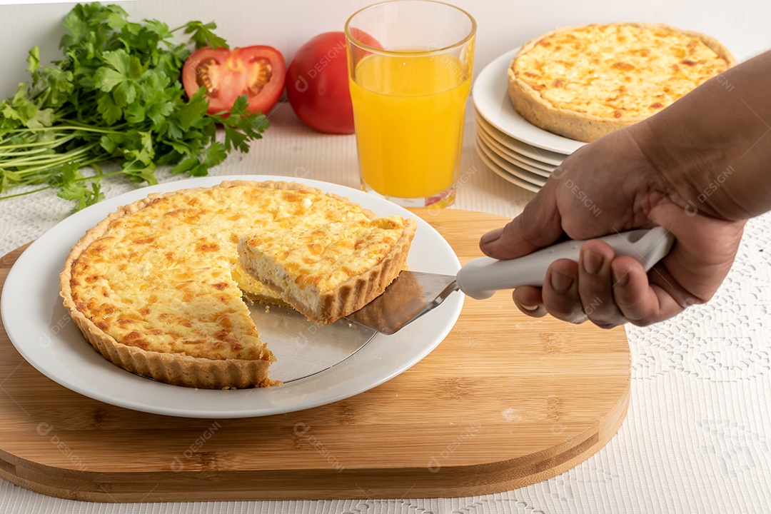 Quiche de queijo mão cortando fatia com fundo de ingredientes