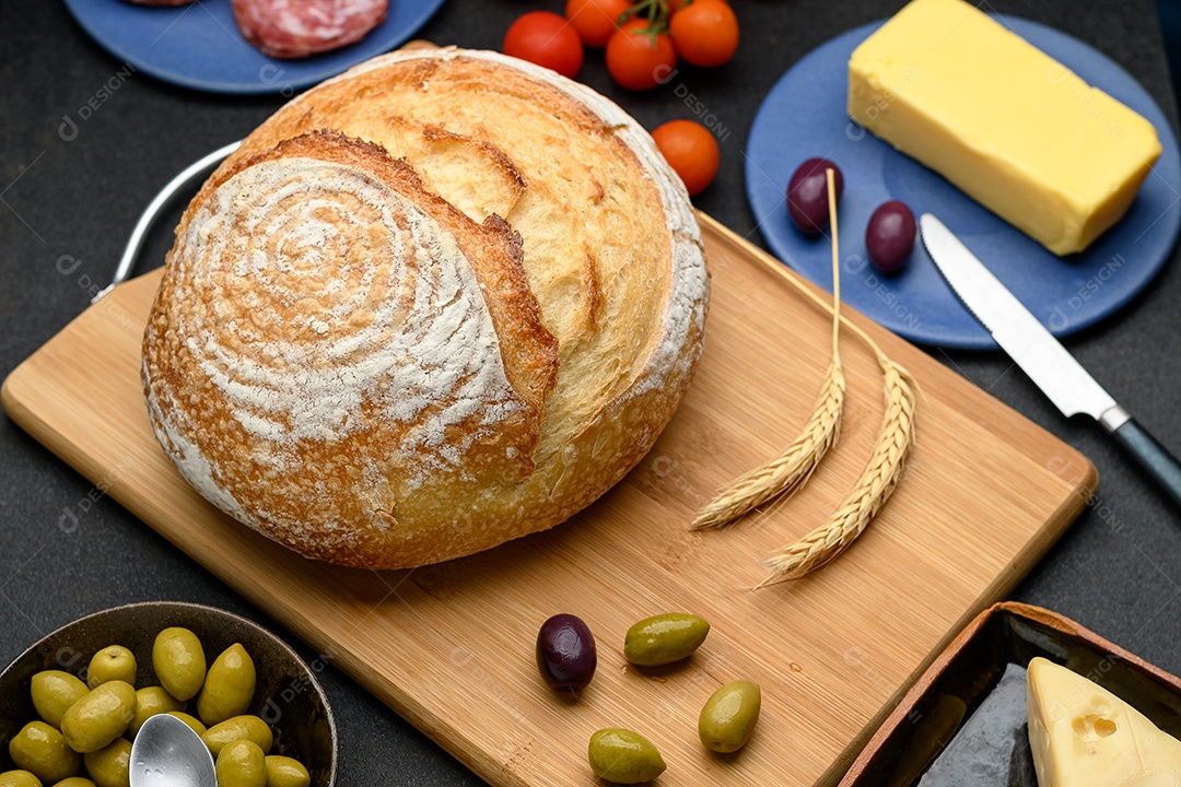 Tábua com pão caseiro em cima e guarnições ao lado