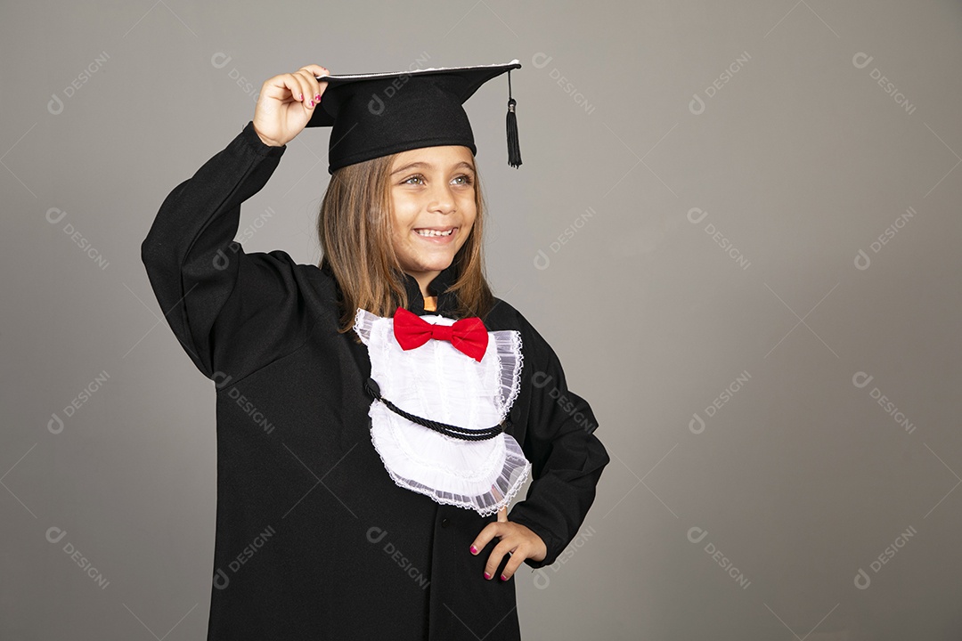 Menina linda com mão no chapéu e e beca para formatura